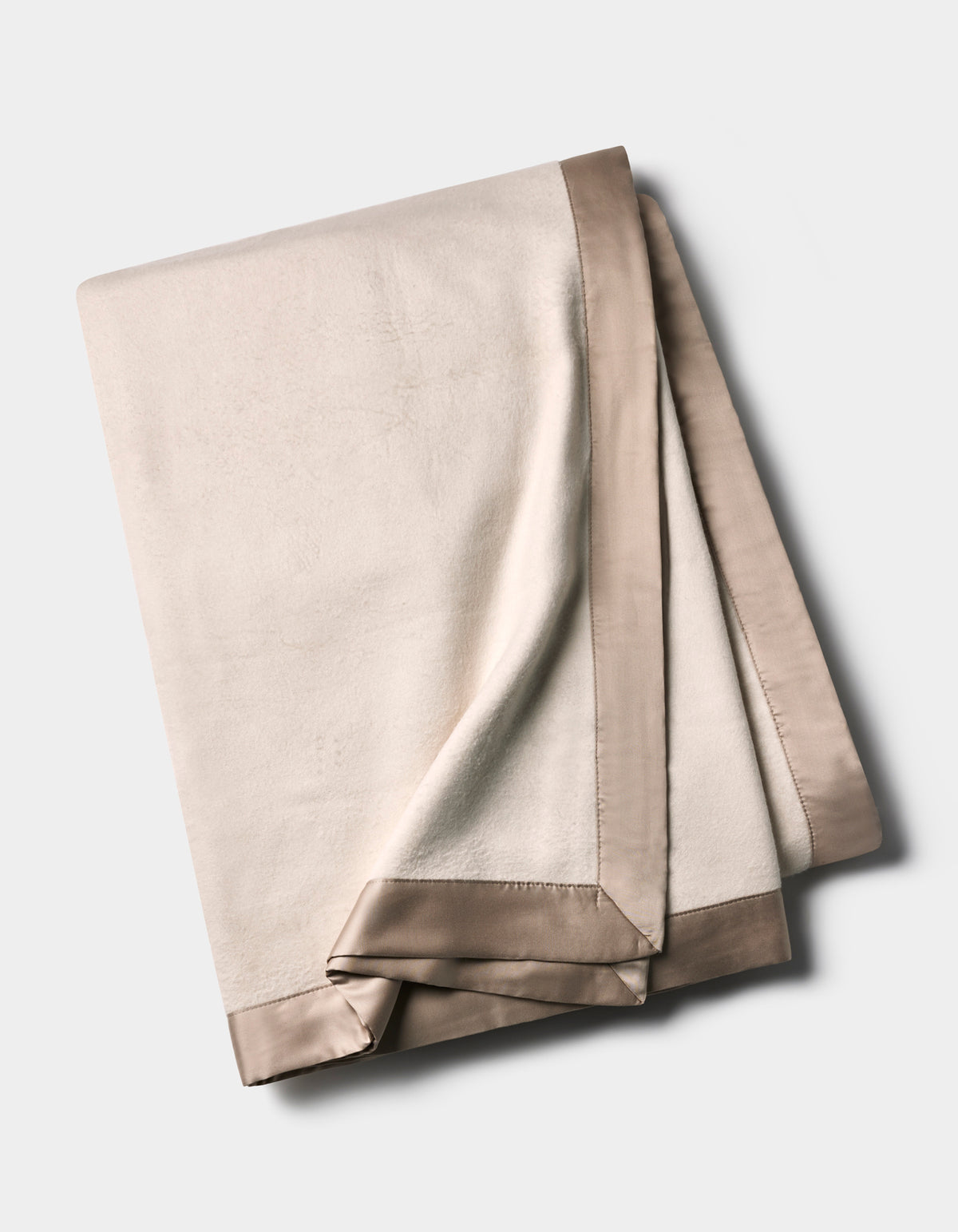 The Cozy Earth Bamboo Blanket is folded and displayed on a neutral background, featuring an ivory color with a smooth, shiny taupe satin trim along the edges.|Color:Oat/Driftwood