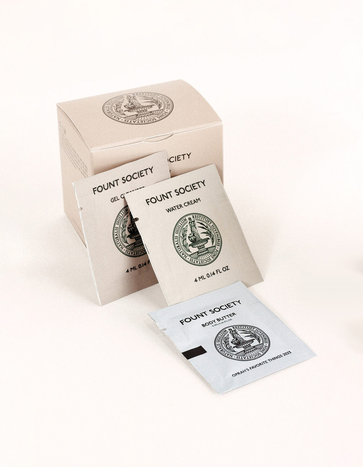 Three sample sachets from the Fount Society Intro Kit by Cozy Earth—Gel Cleanser, Water Cream, and Body Butter—are displayed in front of a beige product box.
