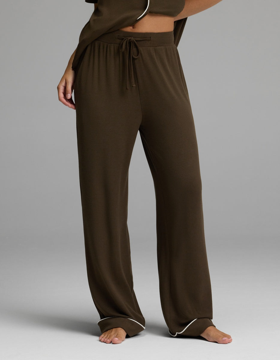 A person is shown from the waist down, standing barefoot on a gray background, wearing Cozy Earth’s Women’s Bamboo Rib-Knit Classic Pajama Pant in brown with a comfortable drawstring waist.|Color:Espresso