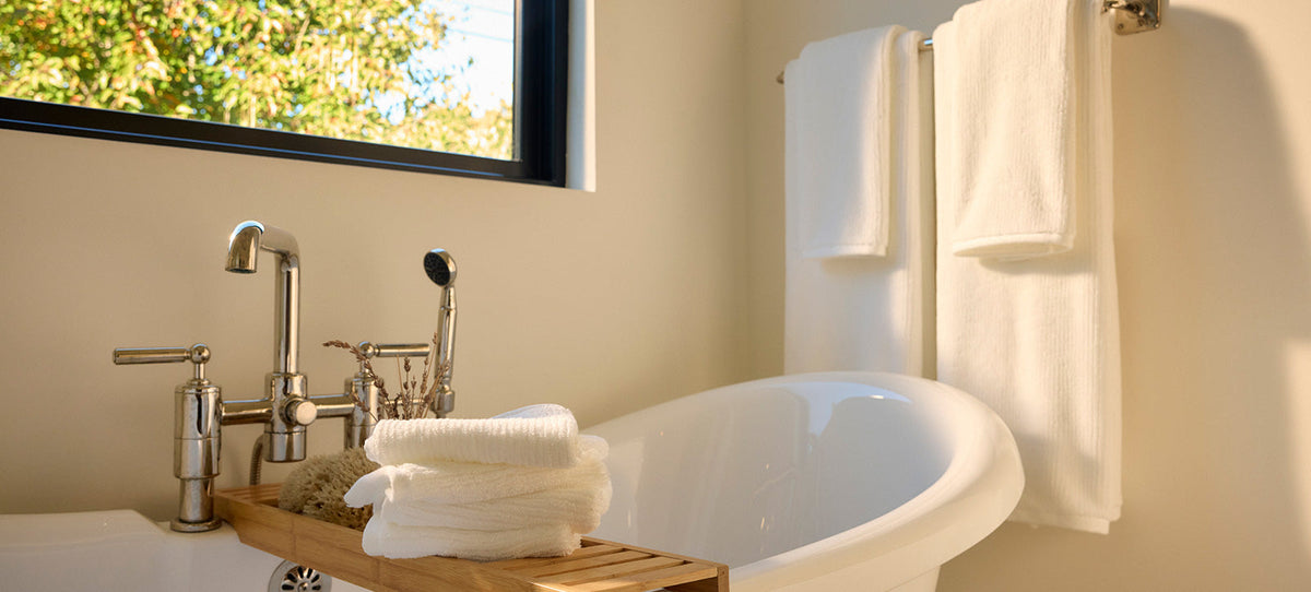 Four white towels hang next to a bathtub