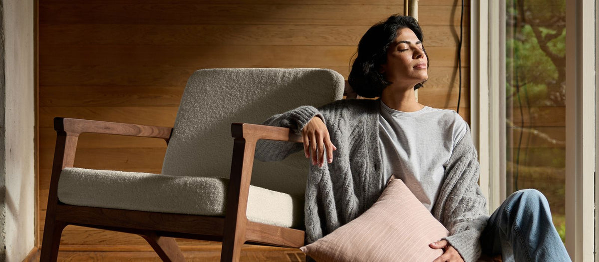 A woman sits next to a Cozy Earth Coronado Lounge Chair holding a decorative pillow