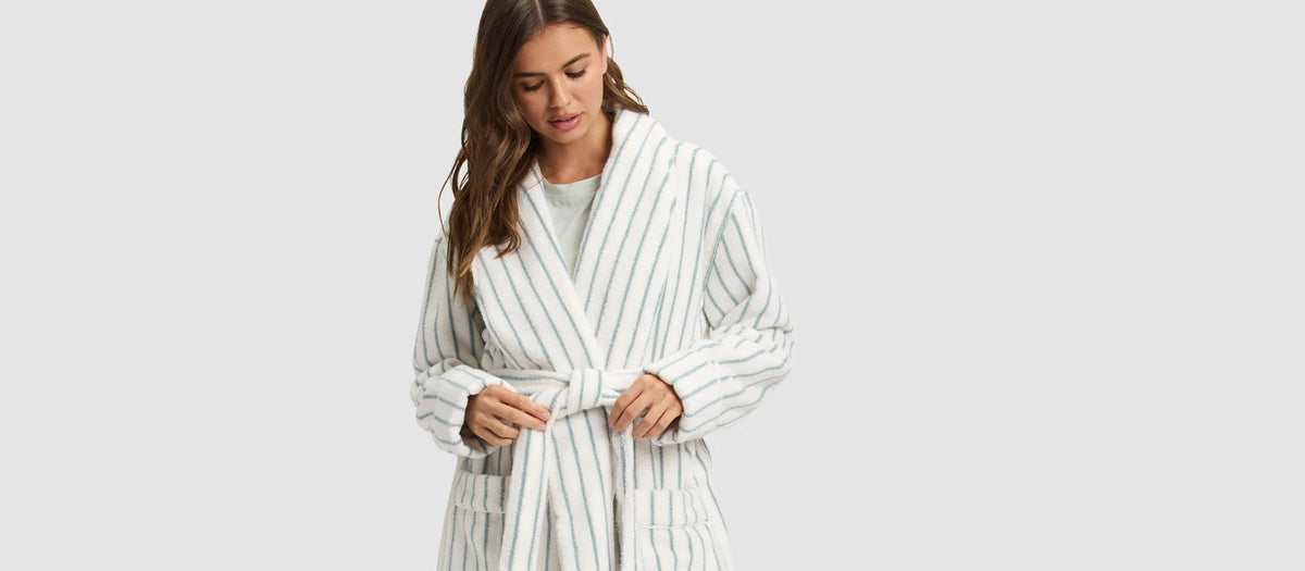 a woman wearing Cozy Earth Striped Luxe Bath Robe stands in front of a grey background