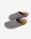 The Lakehouse Clog by Cozy Earth features a minimalist design with grey woolen uppers and natural brown soles. It has a closed toe, open back, and is ideal for indoor wear. A logo is visible on the insole, all showcased on a white background. |Color:Charcoal