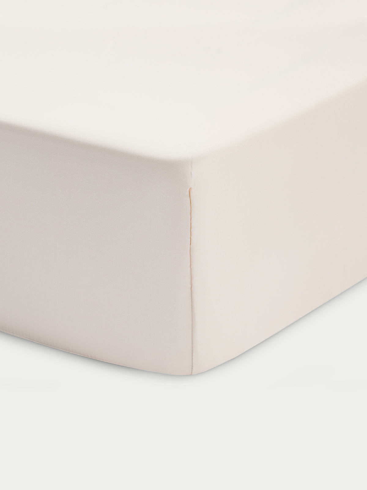 Corner of creme crib sheet with white baackground 