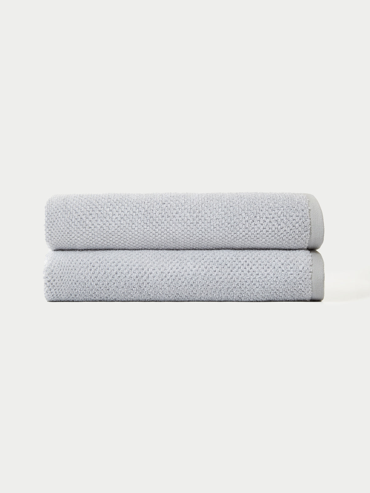 The Complete Nantucket Bath Bundle by Cozy Earth features two neatly folded light gray towels stacked on top of each other against a plain white background.