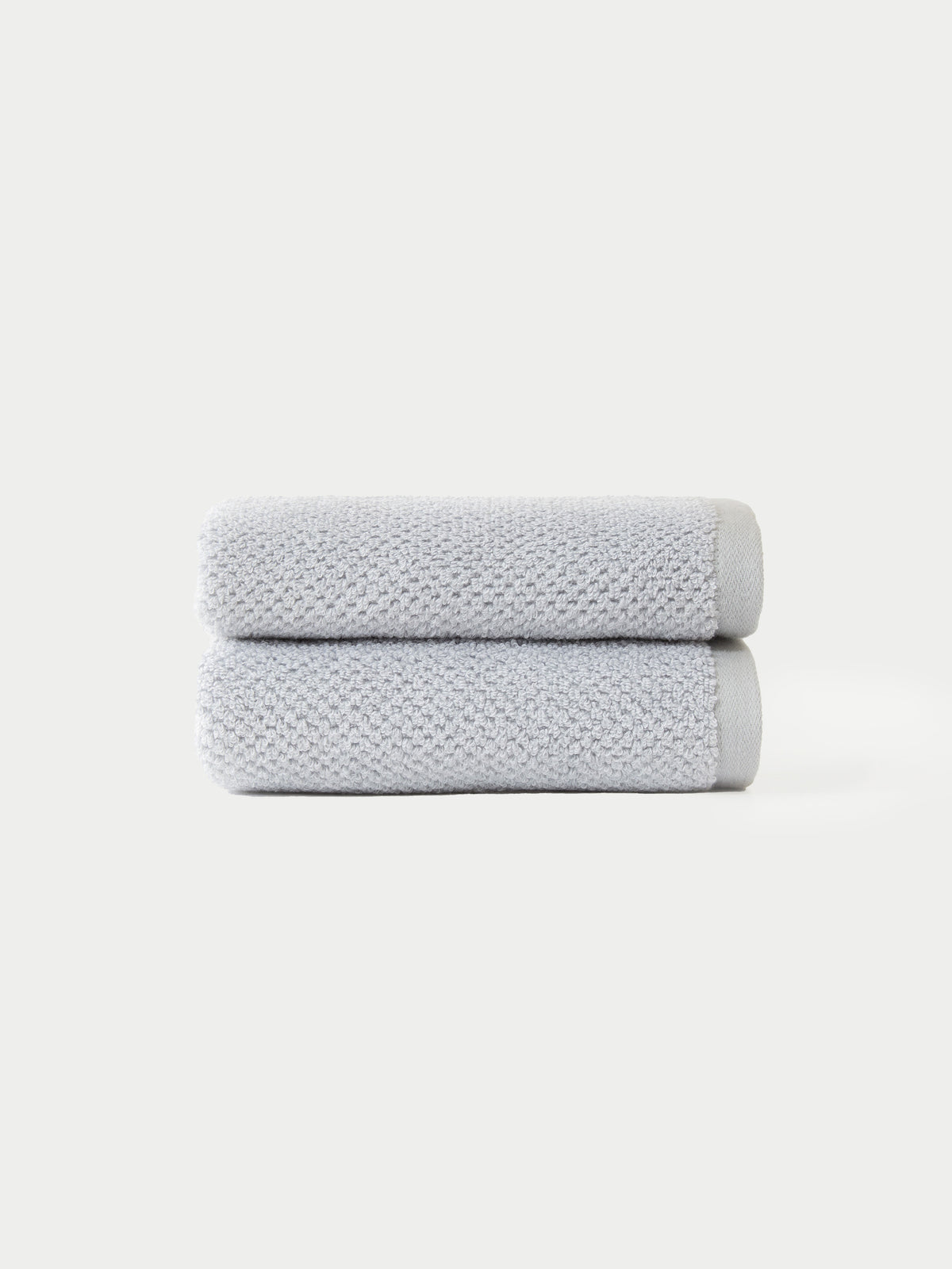 Two Nantucket Bath Towel Set towels by Cozy Earth, neatly folded in light gray and stacked atop each other, displayed against a plain white background.