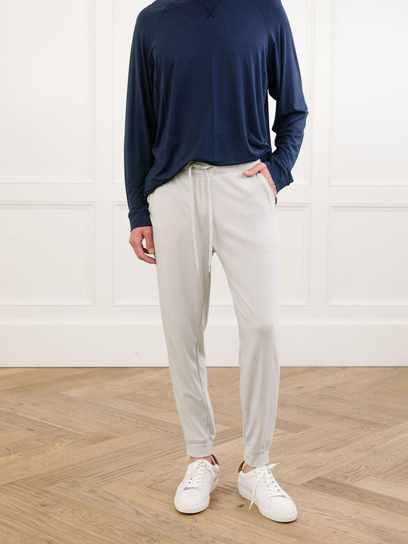 Light Grey/Navy Men's Bamboo Jogger Set. There is a man wearing the jogger set. He is standing in a well lit room in a home.