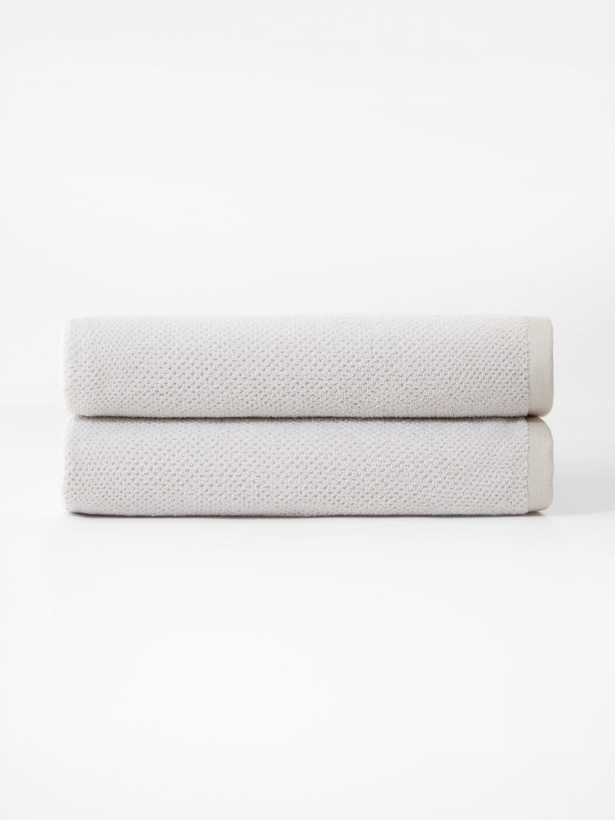 Cozy Earth’s Nantucket Bath Towel Set features two neatly folded, light gray towels stacked together against a plain white background.