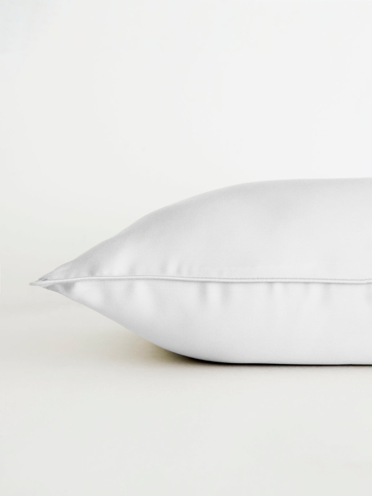 A Bamboo Travel Pillowcase by Cozy Earth is displayed on a white surface, side view against a plain white background, emphasizing its soft texture and smooth finish. 