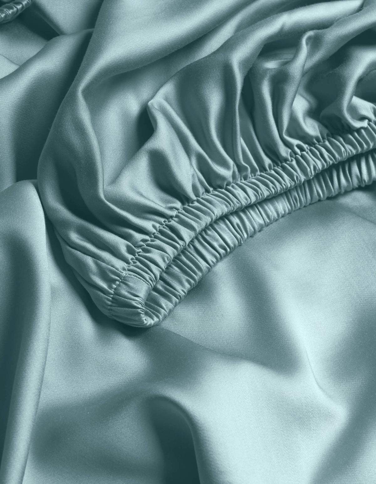 Close-up of Cozy Earth's Bamboo Fitted Sheet in light blue, featuring gathered elastic edges and a smooth, shiny texture with soft folds.