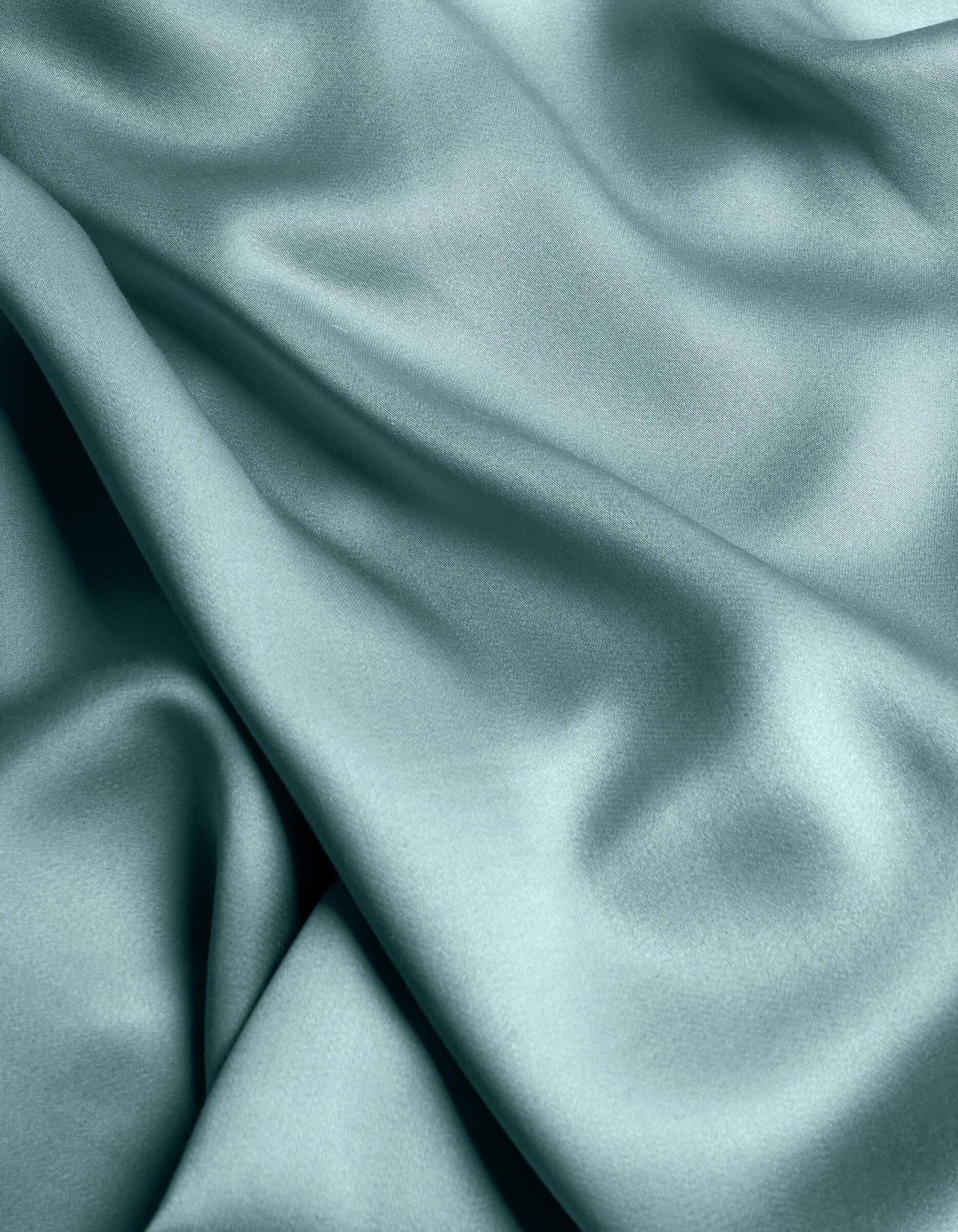 The Cozy Earth Bamboo Sheet Set features smooth, light blue satin fabric with gentle folds and a soft, flowing texture for a shiny, elegant look.