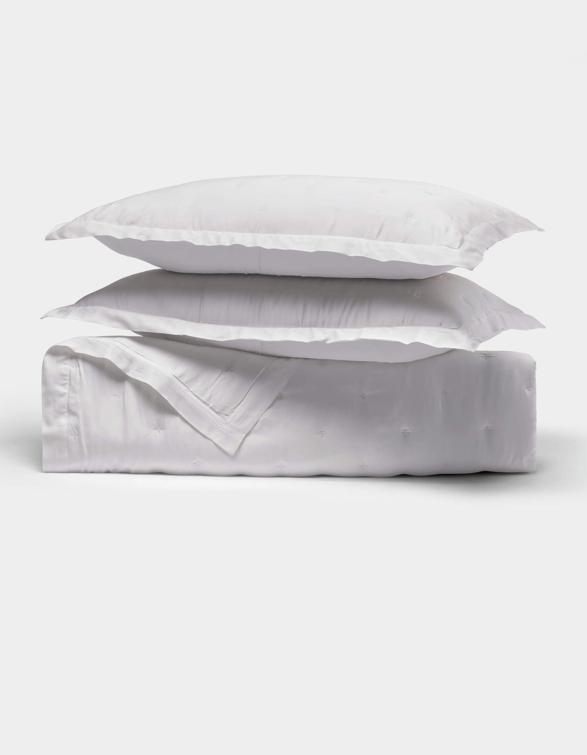 The Cozy Earth Bamboo Quilt Bundle features two fluffy white pillows stacked on a neatly folded white comforter, all shown against a plain white background.|Color:White