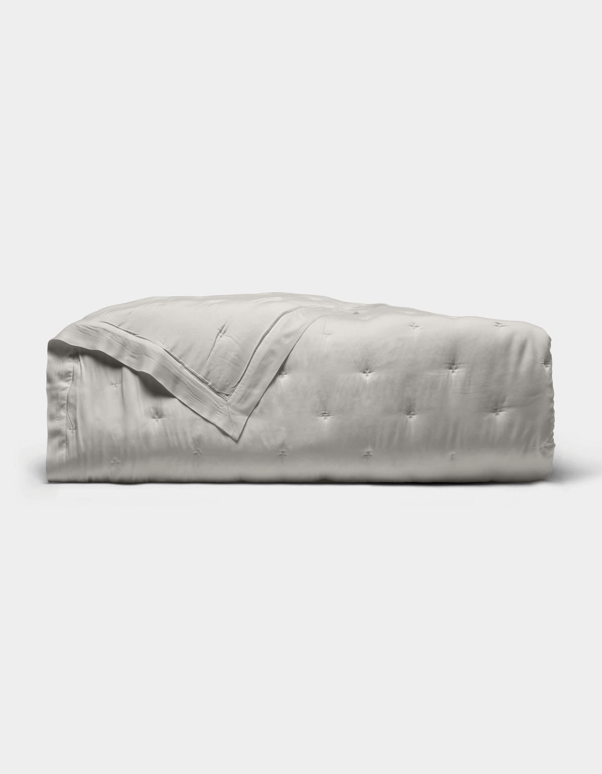 The Cozy Earth Bamboo Quilt, featuring a subtle tufted pattern and light gray color, is neatly folded against a plain white background.