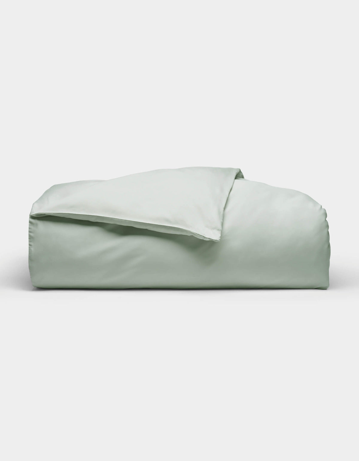 The Soft-Wash Cotton Duvet Cover by Cozy Earth, shown neatly folded in light green, is displayed against a plain white background.|Color:Laurel