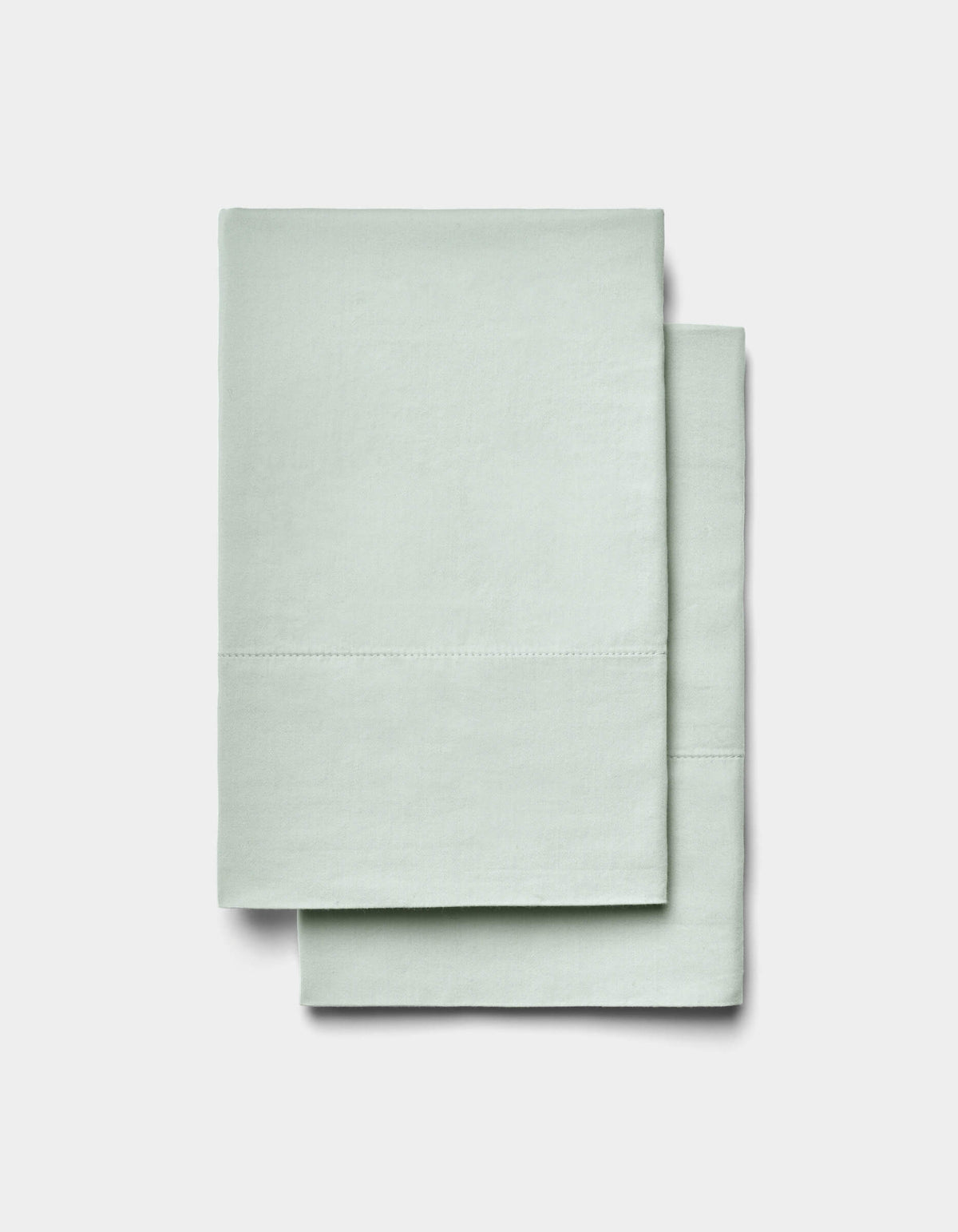 Two neatly folded Soft-Wash Cotton Sheet Set items by Cozy Earth in light mint green are stacked on a plain white background.