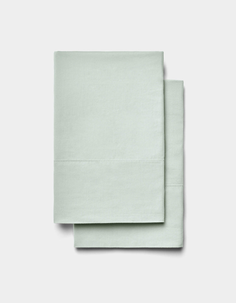 Two neatly folded Soft-Wash Cotton Sheet Set items by Cozy Earth in light mint green are stacked on a plain white background.