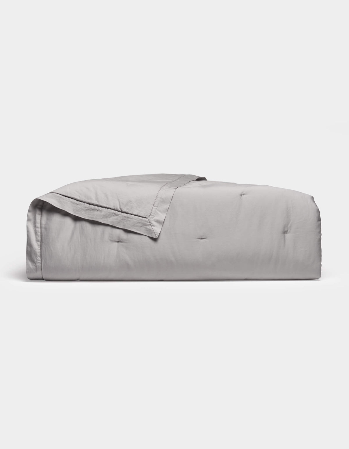 The Cozy Earth Soft-Wash Cotton Quilt in light gray features a subtle quilted pattern and is neatly folded, displayed against a plain white background.|Color:Dew