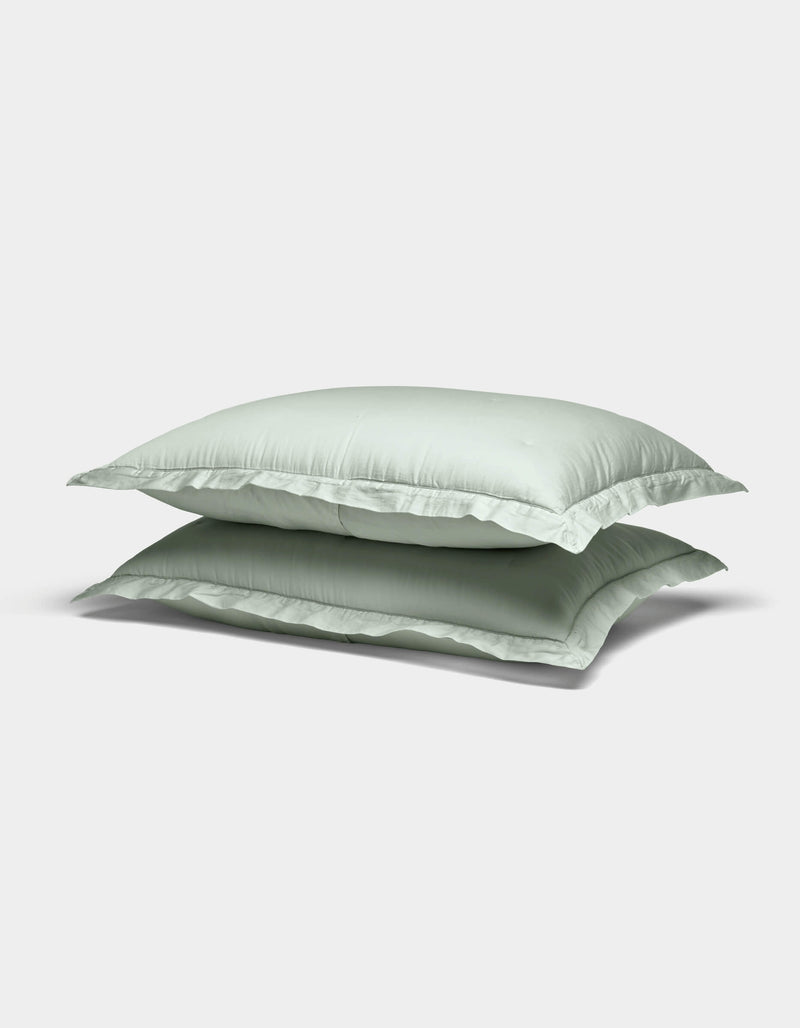 Two Soft-Wash Cotton Shams by Cozy Earth in light green are stacked atop each other against a plain white background.