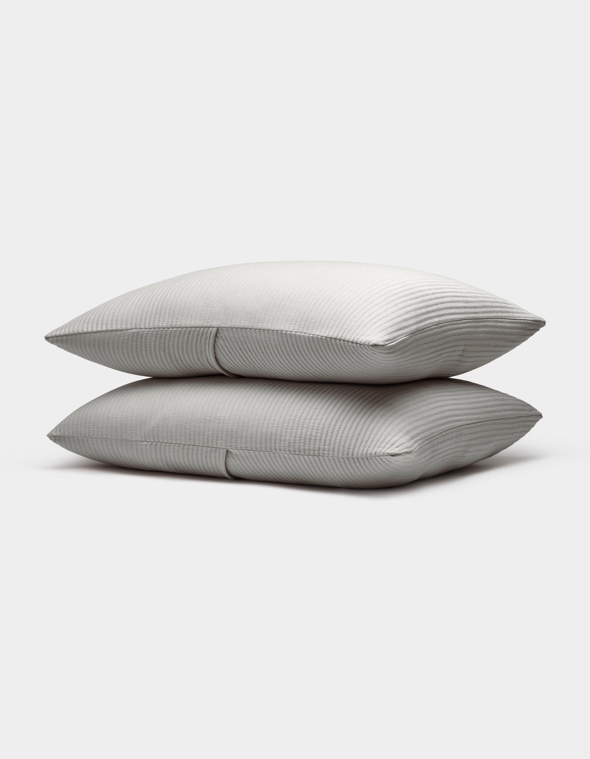 Two neatly stacked Bamboo Coverlet Shams by Cozy Earth, light gray with a subtle striped pattern, are displayed on a plain white background.