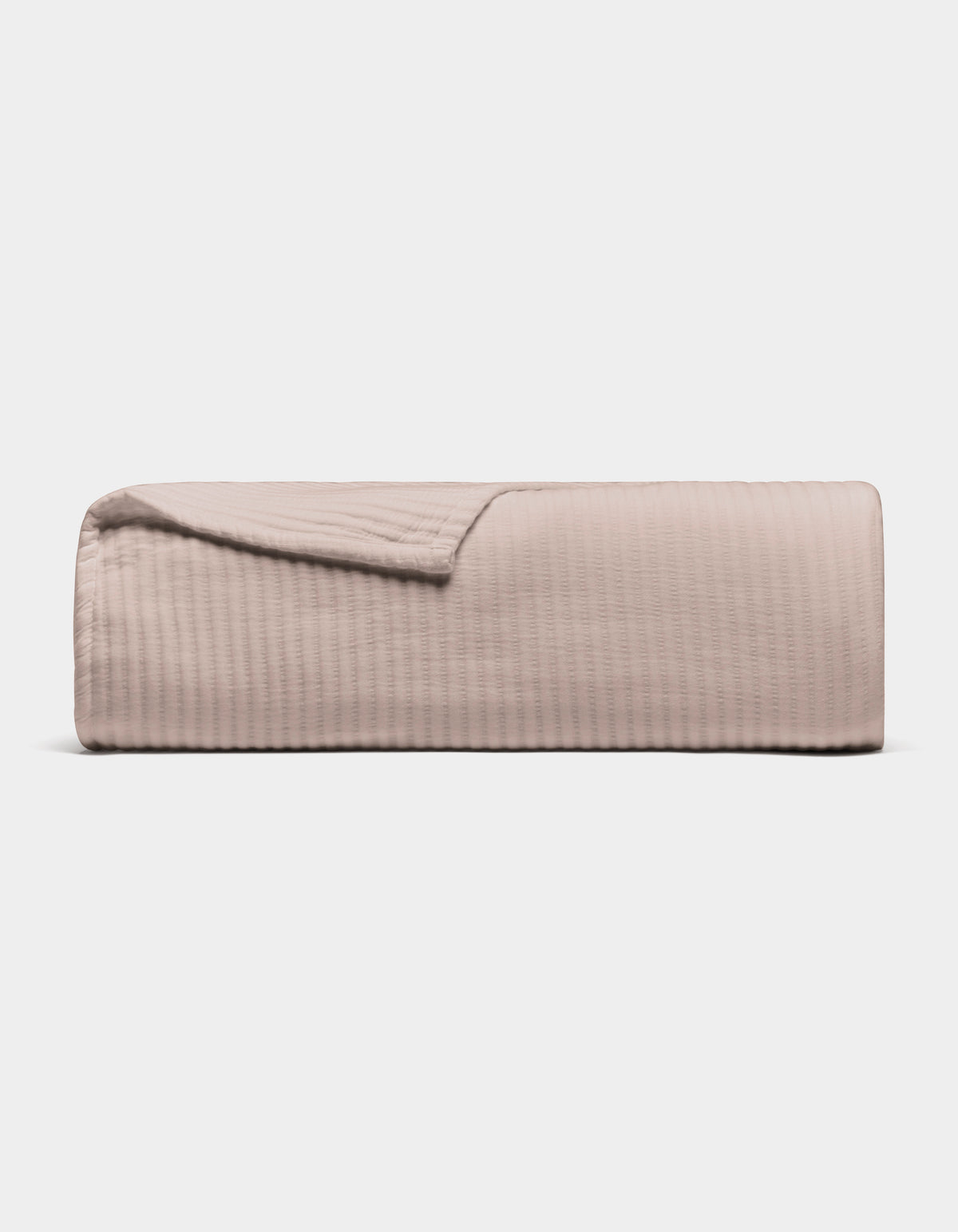 The Cozy Earth Bamboo Coverlet, shown folded in light beige with a subtle stitched texture, is displayed against a plain white background.