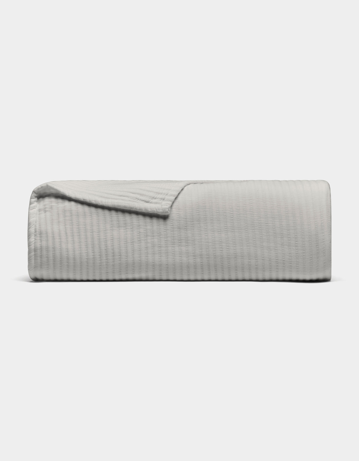 The Cozy Earth Bamboo Coverlet, shown in light gray with a textured design, is neatly folded against a plain white background. A corner is turned down to display its soft material.|Color:Light Grey