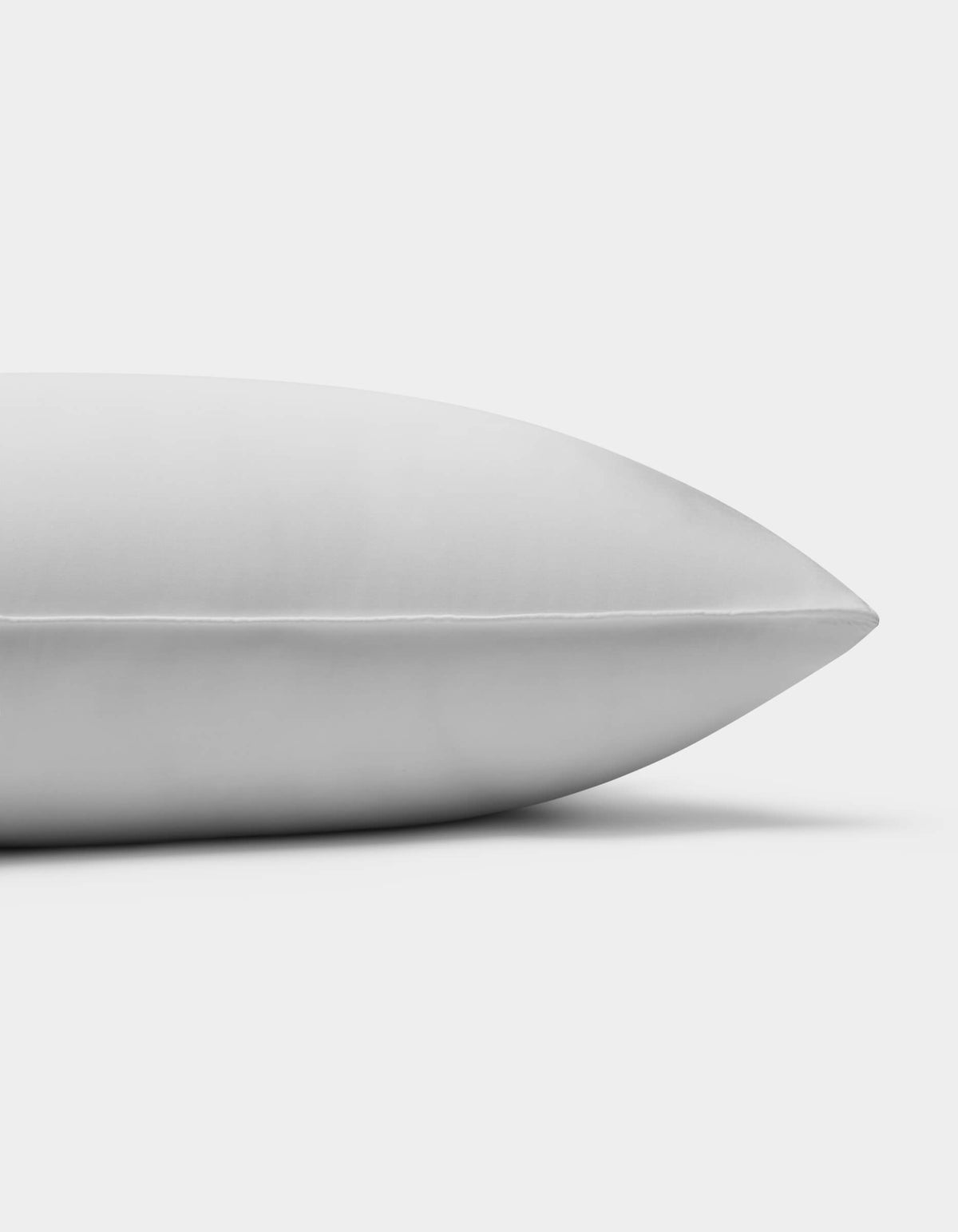 A close-up side view of the Cozy Earth Down Alternative Insert Bundle pillow on a white background, highlighting its smooth, clean surface and pointed end.