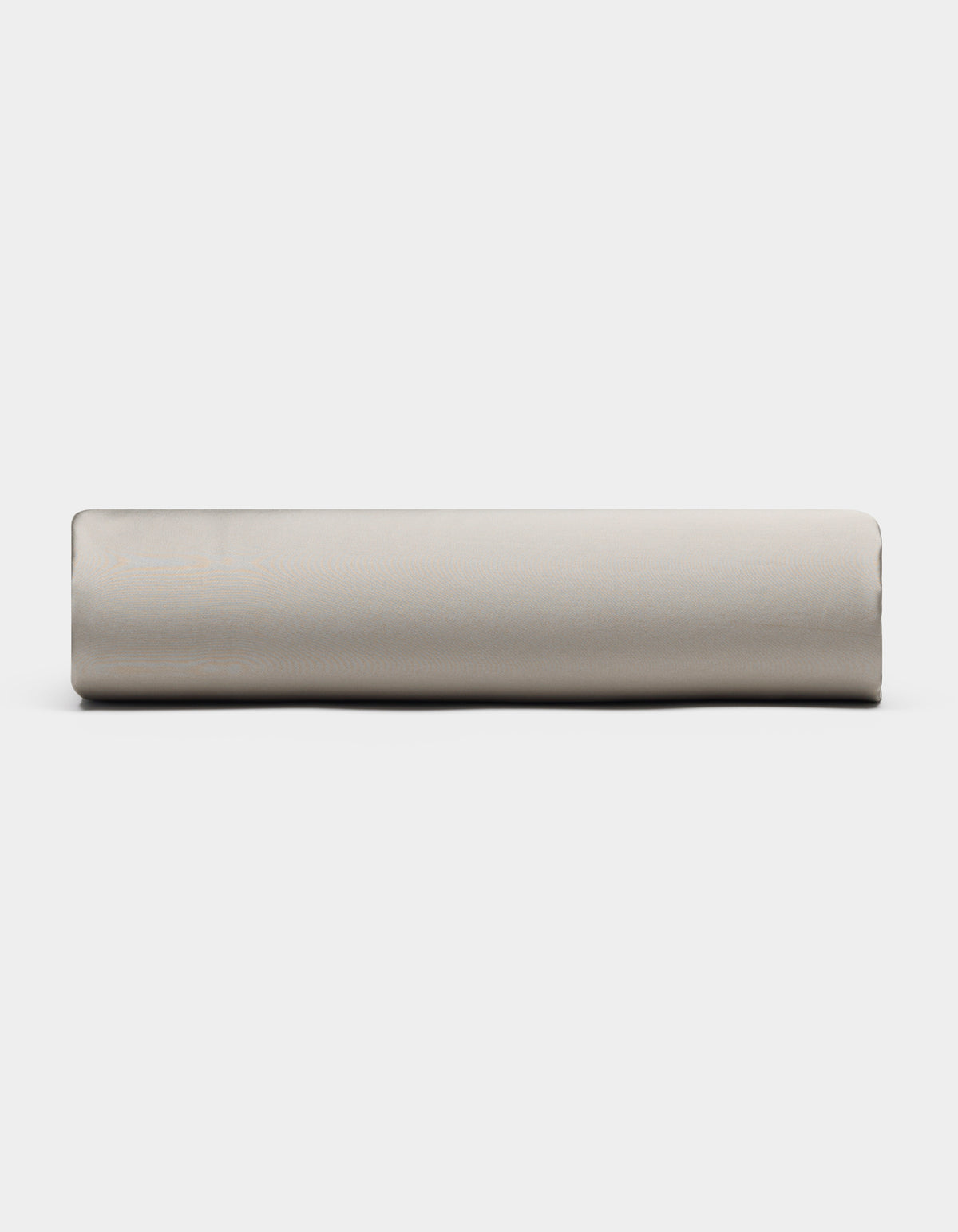 A Bamboo Fitted Sheet by Cozy Earth, in light gray, is rolled up and placed horizontally against a plain white background, viewed from the side.