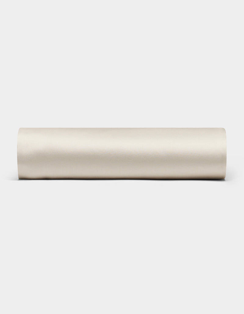 The Cozy Earth Bamboo Fitted Sheet, shown rolled up in beige, is displayed horizontally against a plain white background.