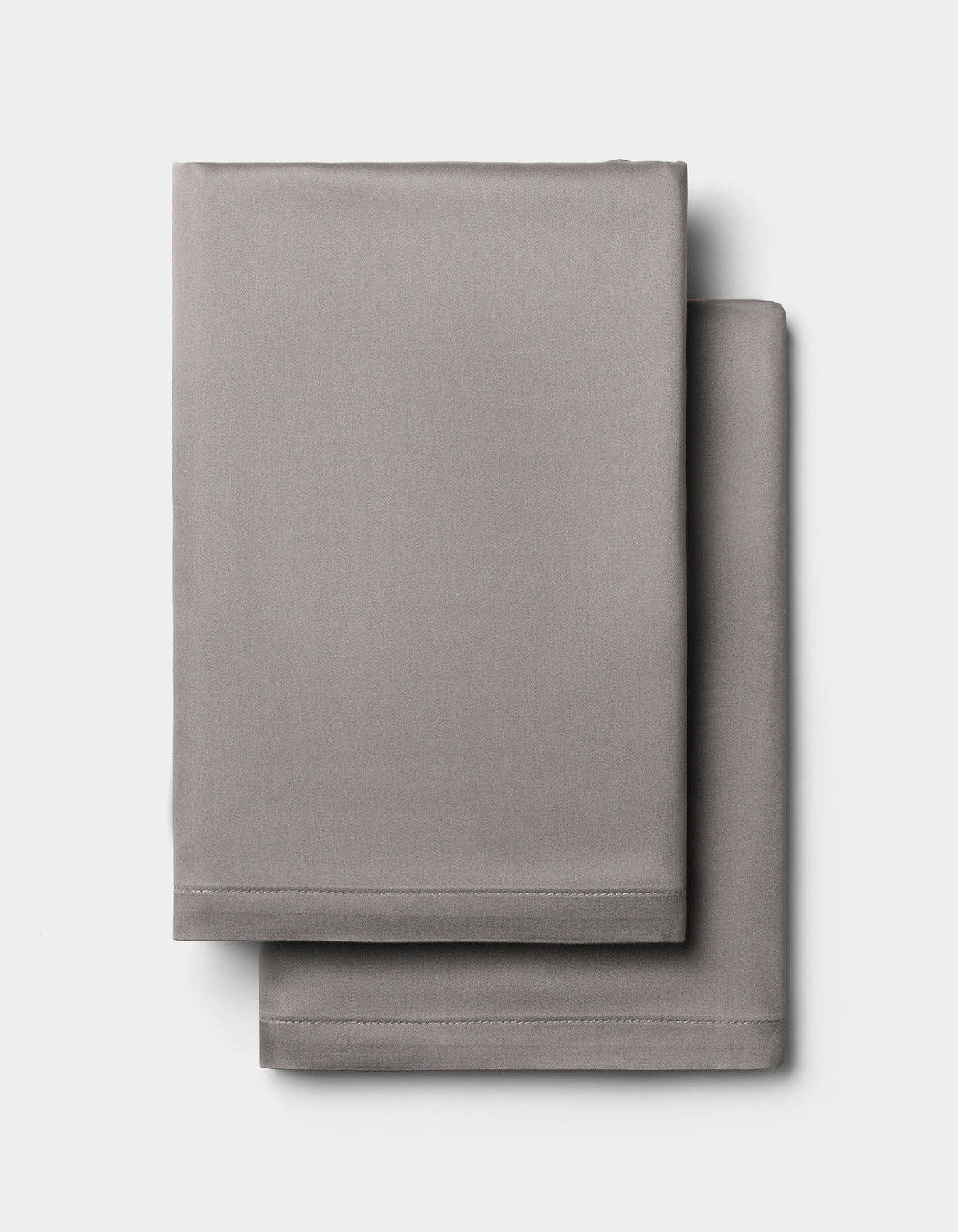 Two light gray Cozy Earth Bamboo Pillowcases, neatly folded and stacked against a plain white background.