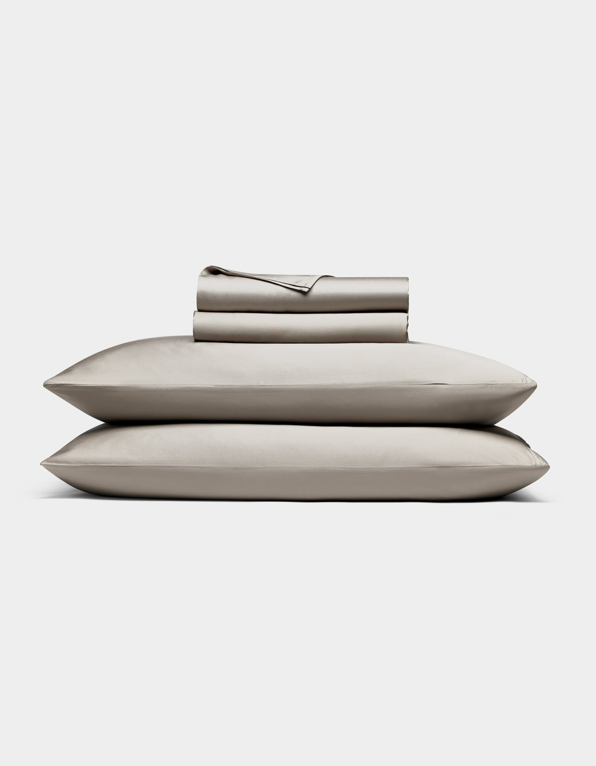 The Cozy Earth Bamboo Sheet Set, in light gray, includes neatly folded bed sheets and pillowcases stacked atop two pillows, all shown against a plain white background.