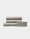 The Cozy Earth Bamboo Bedding Core Bundle, featuring neatly folded light gray sheets and pillowcases, is stacked on a white background with three larger sheets on the left and pillowcases on the right.|Color:Light Grey