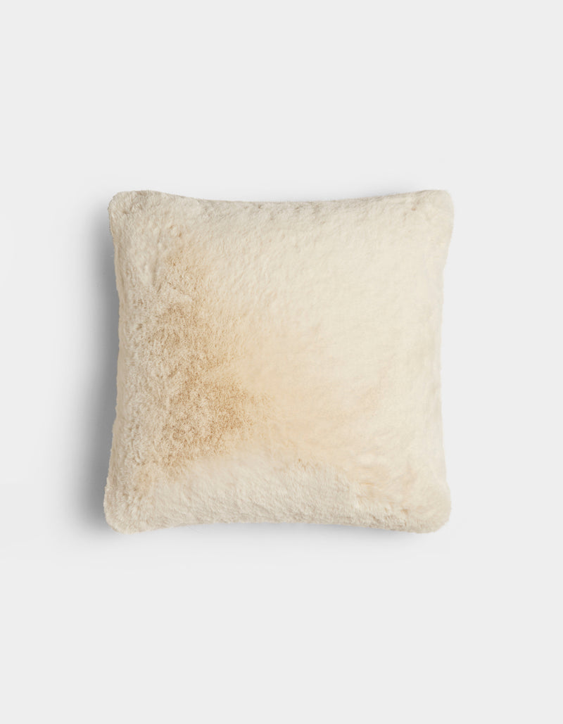 The Cozy Earth Cuddle Pillow is a square, fluffy, cream-colored pillow with a subtle light brown stain on one side, shown against a plain white background.