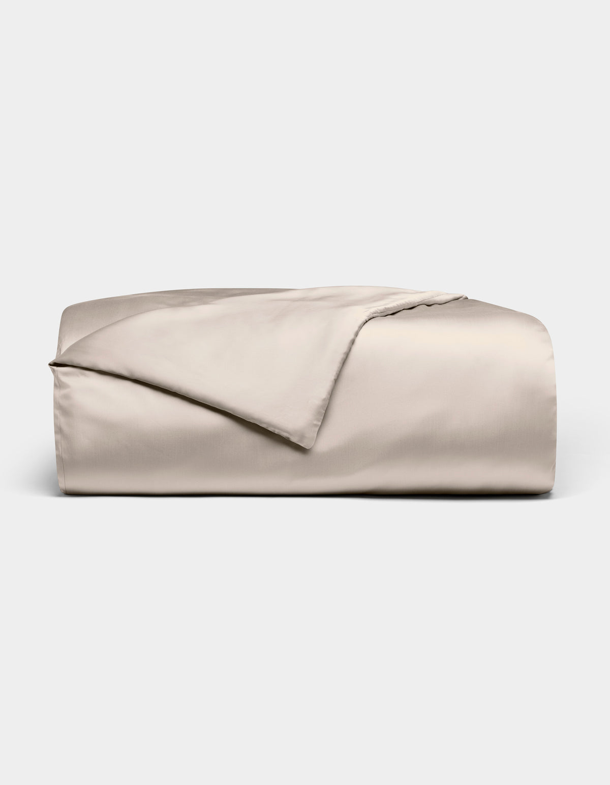 The Bamboo Duvet Cover by Cozy Earth is shown neatly folded in light beige with a smooth, shiny finish against a white background; one corner is flipped open to reveal the inner side.
