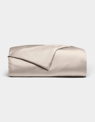 The Bamboo Duvet Cover by Cozy Earth is shown neatly folded in light beige with a smooth, shiny finish against a white background; one corner is flipped open to reveal the inner side.|Color:Driftwood