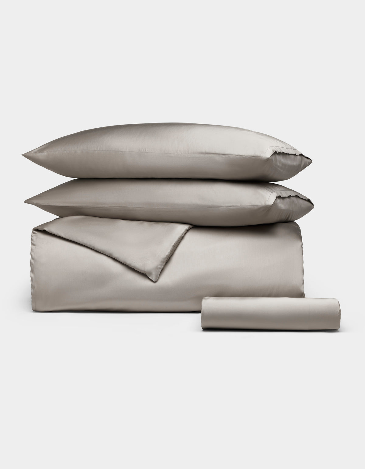 The Cozy Earth Bamboo Bedding Essential Bundle features neatly folded light gray bedding—a comforter, two stacked pillows, and a rolled sheet—displayed on a plain white background.