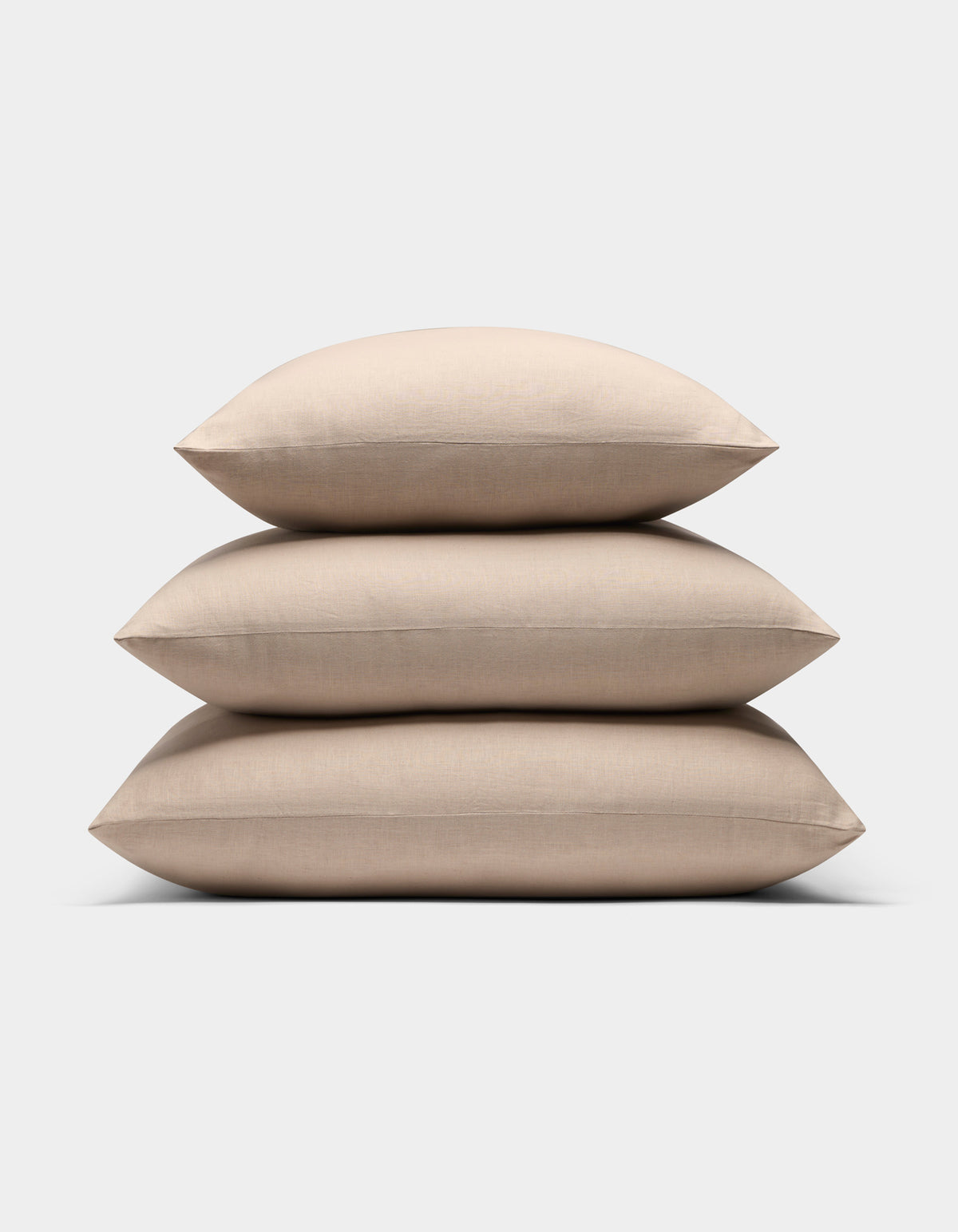 Three Cozy Earth Linen Throw Pillows in beige are stacked neatly against a plain white background.