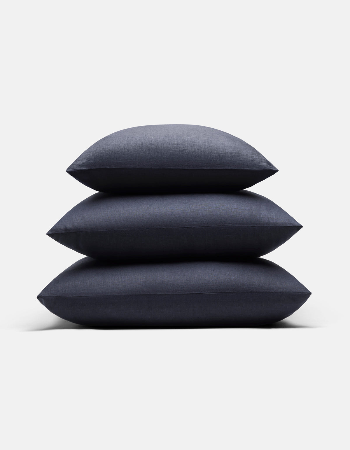 Three Cozy Earth Linen Throw Pillows in dark gray are stacked neatly against a plain white background.