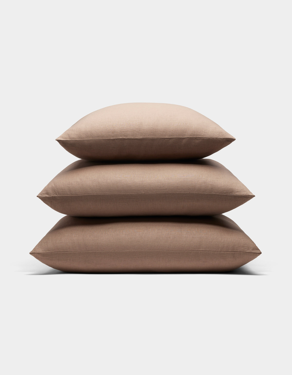 Three Cozy Earth Linen Throw Pillows are stacked neatly on top of each other against a plain white background.