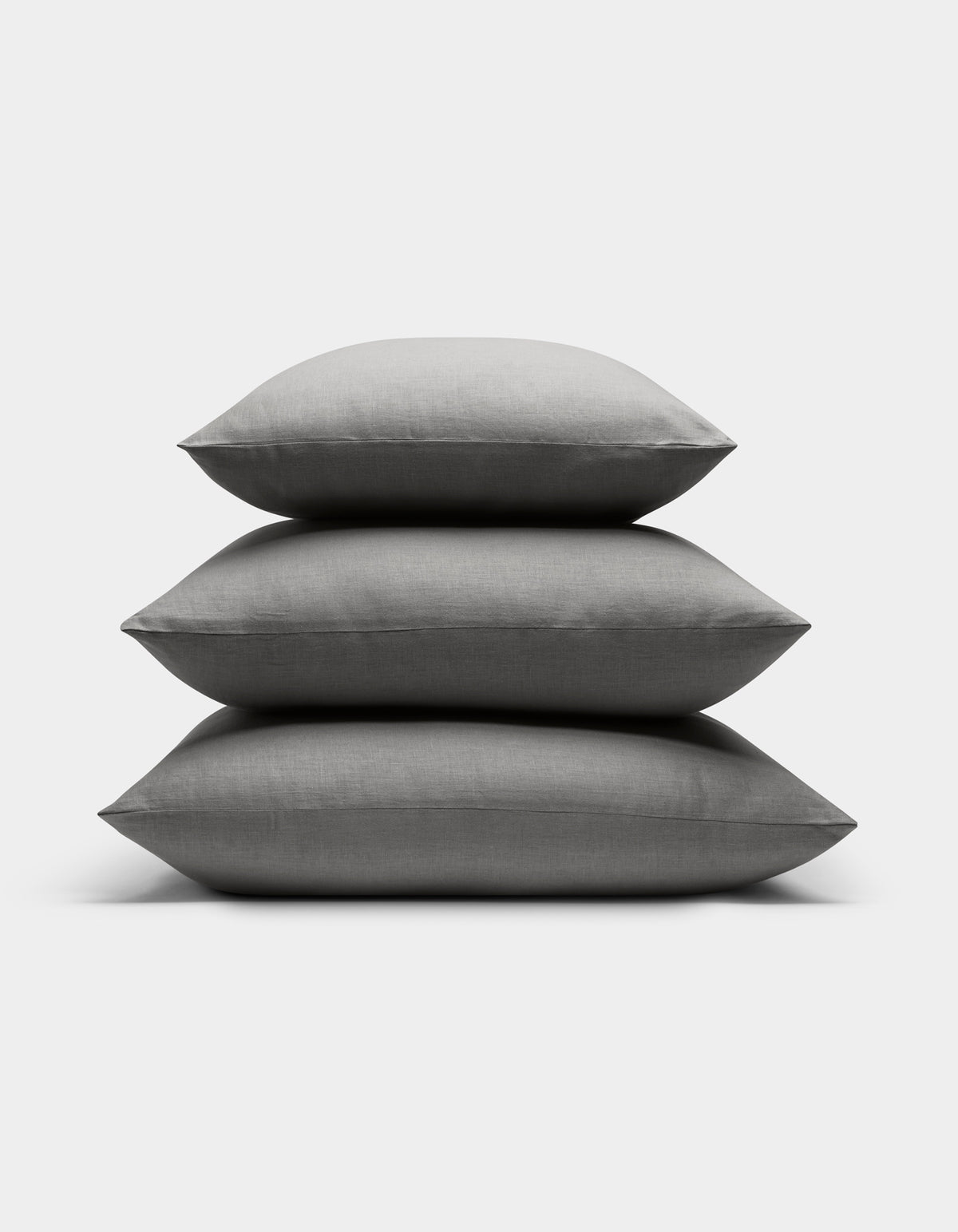 Three Cozy Earth Linen Throw Pillows are stacked neatly atop each other against a plain white background.