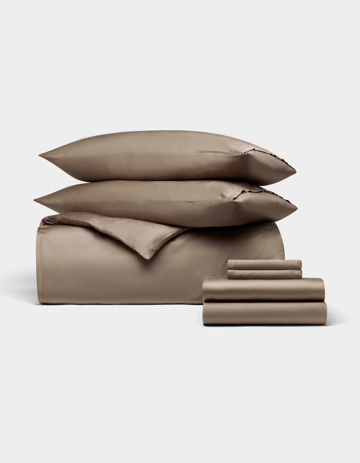 The Bamboo Bedding Ultimate Bundle by Cozy Earth features taupe-colored sheets, a fitted sheet, flat sheet, pillowcases, and two stacked pillows, all neatly arranged against a plain white background.|Color:Walnut