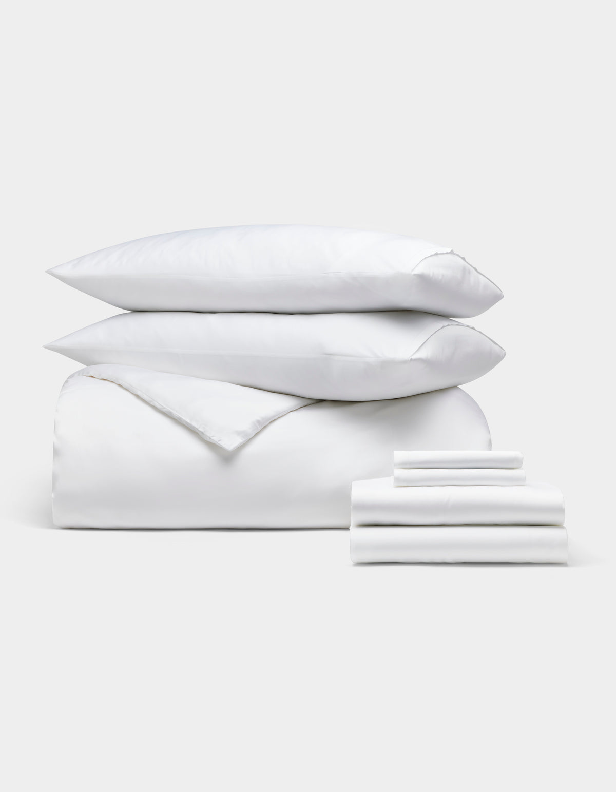The Cozy Earth Bamboo Bedding Ultimate Bundle, featuring two pillows stacked on a comforter and folded sheets, is neatly displayed against a plain light gray background.