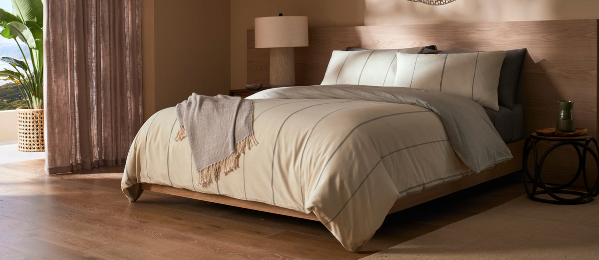 Neatly made bed with Cozy Earth Baja bedding in a bedroom setting.