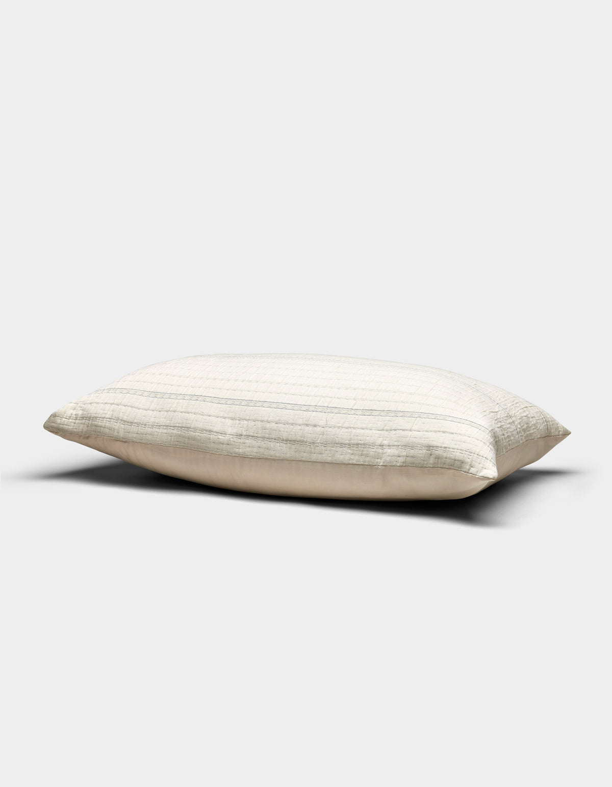 The Baja Matelasse Sham by Cozy Earth, in a cream shade with subtle horizontal stripes, rests on a plain light gray background. Its soft, gently flattened appearance suggests both comfort and support.