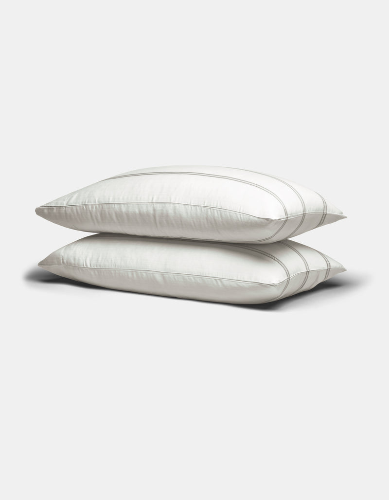 Two Cozy Earth Bamboo Pillowcases in white with subtle gray stripes are stacked on a plain light gray background.