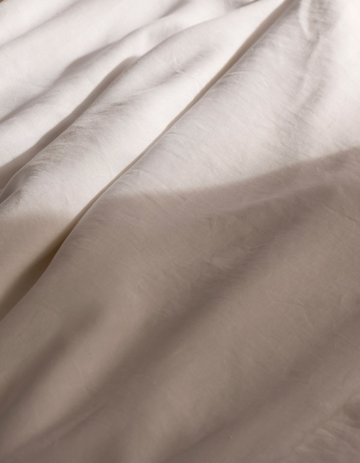 Soft sunlight casts gentle shadows across the Cozy Earth Linen Duvet Cover, its light-hued fabric creating a calm and cozy atmosphere.