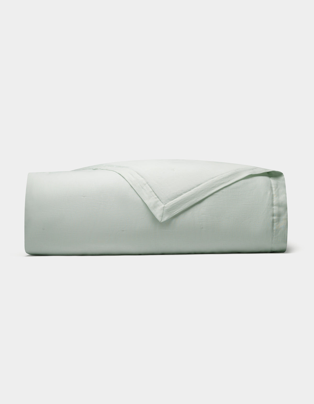 The Cozy Earth Linen Quilt, in a light green shade, is neatly folded and displayed against a plain white background.|Color:Mist