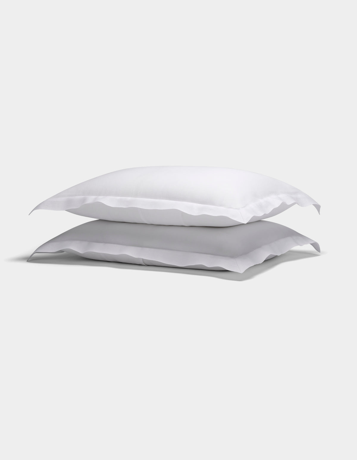Two Cozy Earth Linen Shams with ruffled edges are stacked neatly against a plain light background.|Color:White