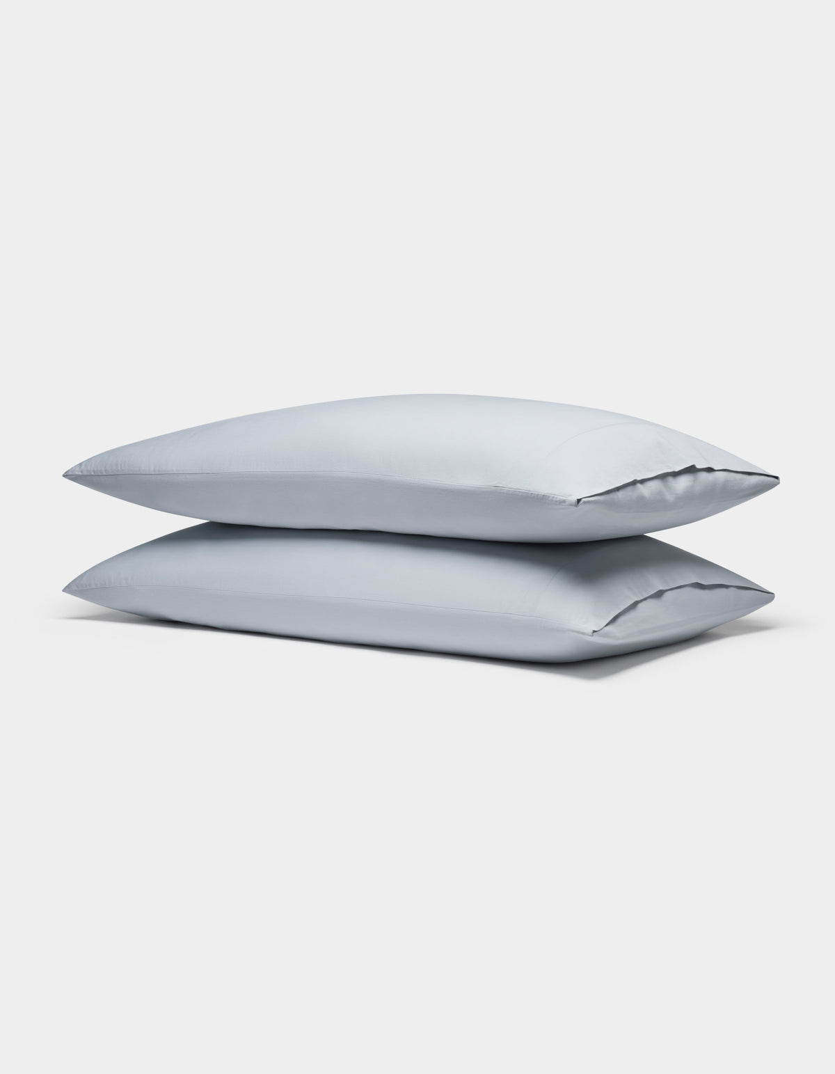 Two Soft-Wash Cotton Pillowcases by Cozy Earth, in light gray, are neatly stacked against a plain white background.