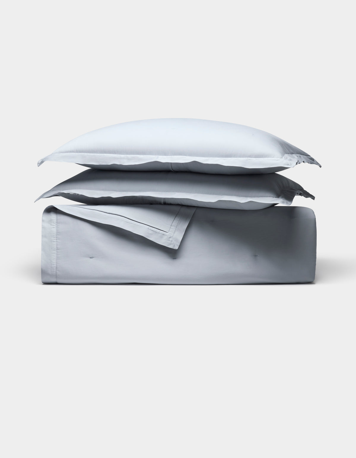 The Cozy Earth Soft-Wash Cotton Quilt Bundle, featuring two pillows and a folded light gray sheet, is neatly stacked and displayed against a plain white background.|Color:Shore