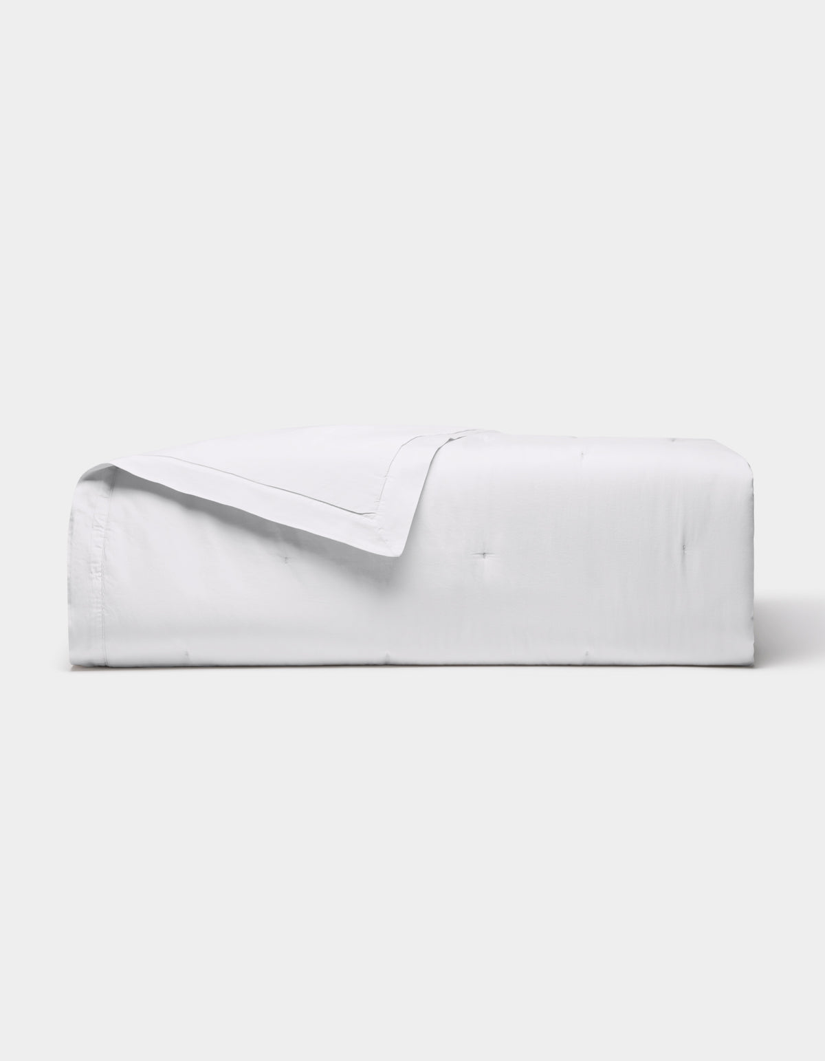 The Cozy Earth Soft-Wash Cotton Quilt is neatly folded with one corner turned down, showcased against a plain light gray background.|Color:White